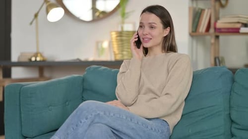 Woman Talking on Phone While Sitting on Sofa