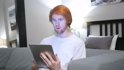 Man Using Tablet Shocked Indoors on Couch