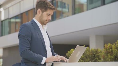 Young Man Using Laptop in Modern City Setting