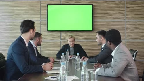 Business People in Meeting with Green Screen Display