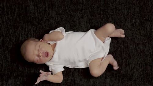 Peaceful Newborn Baby Lying on Dark Blanket
