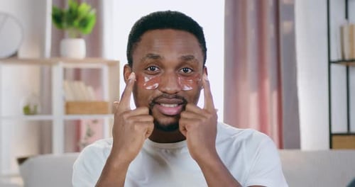 Man Applying Skincare Eye Patches to Face