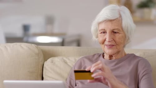 Senior Woman Using Laptop with Credit Card at Home
