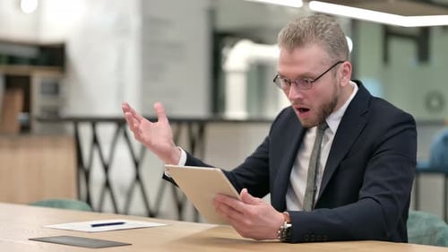 Disappointed Businessman Reacting To Loss on Tablet in Office