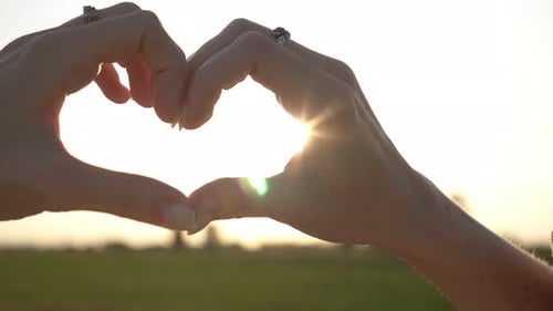 Hands Forming Heart Shape at Sunset