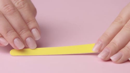 Woman Filing Nails with Yellow File at Home