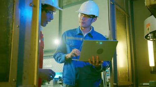 Engineers Reviewing Laptop Data in Manufacturing Environment