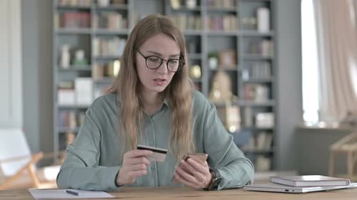 Upset Woman Doing Online Shopping Through Credit Card on Laptop