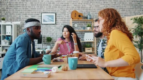 Group of Happy Young People Talking Laughing Working at Desk in Office