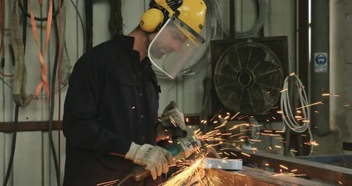 Worker using a metal grinder in a metal workshop