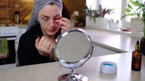 Woman Applying Cosmetic Eye Patches at Home