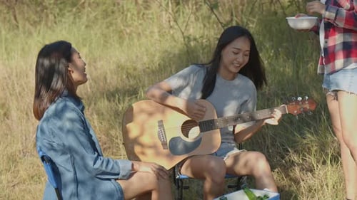 Friends Playing Guitar and Eating Outdoors