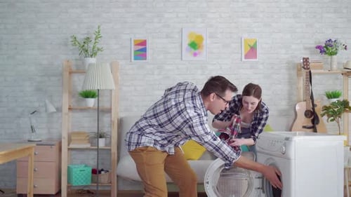 Couple Loading Washing Machine and Dancing at Home