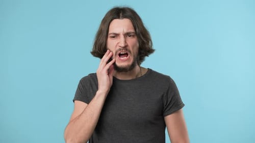 Portrait of Young Bearded Man Suffering From Toothache or Touching Jawbone and Expressing Pain on