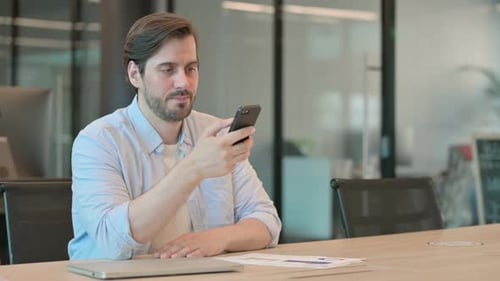 Reifer erwachsener Mann mit Smartphone im Büro