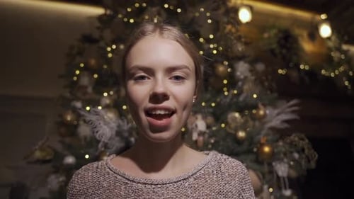 Young Woman Opening Christmas Gift in Front of Tree