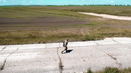 Aerial View of a Lone Tired Soldier Walks Along an Old Concrete Road