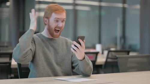 Red-Haired Man Excited About News on His Phone