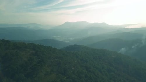 Scenic Flight Over Beautiful Mountain Scape with Bright Sky and Clouds on Summer