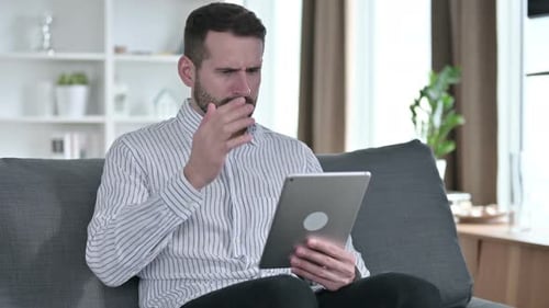 Man Frustrated with Tablet on Couch at Home