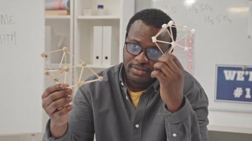 Enthusiastic Teacher Holds Science Models in Classroom