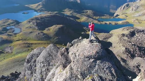 Photographer in Red Coat on Top of Mountain