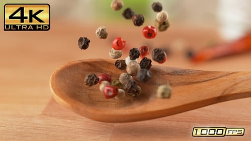 Colorful peppercorns falling into a wooden spoon
