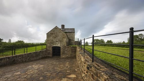 Zeitraffer eines historischen Kalkofengebäudes während des Tages mit vorbeiziehenden Wolken in ländlicher Landschaft
