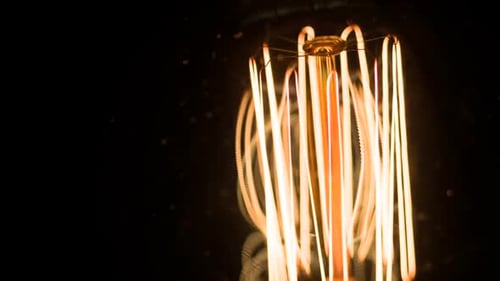 Glowing Light Bulb Filament Against Black Background