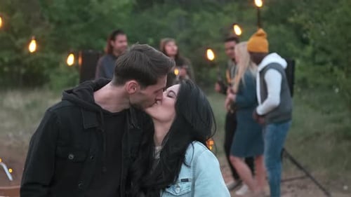 Affectionate Couple Kissing Amongst Friends At Outdoor Party
