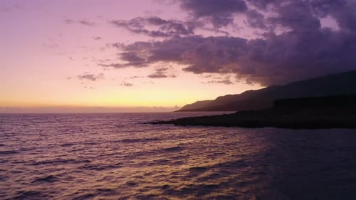 Aerial view of Purple Sunset above the Sea water and ripple waves. Flying over Calm Ocean.