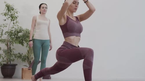 Female Trainer Watching Sportswoman Doing Yoga