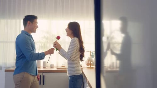 Loving Couple Embrace in Bright Kitchen with Rose