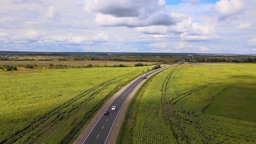 Luftaufnahme der Intercity-Straße zwischen grünen landwirtschaftlichen Feldern mit schnell fahrenden Autos