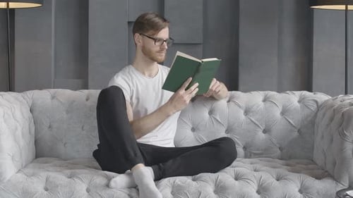 Man Reads Book on Couch
