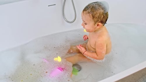 Baby Girl Playing with Bath Toys in Tub