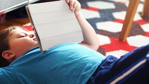 Young Child Lying on Rug with Tablet