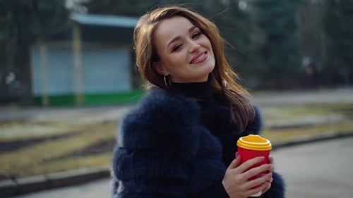Smiling model with coffee outdoors