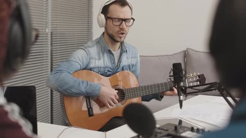 Man Playing Guitar and Singing into Microphone