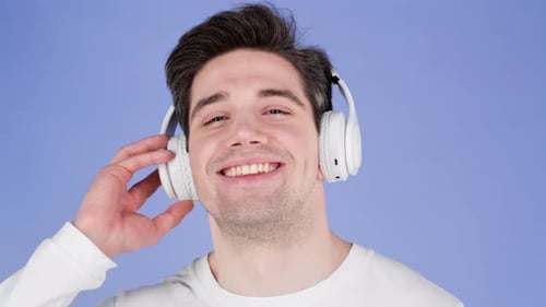 Charming Young Man Listening to Music with Wireless Headphones Guy Having Fun Smiling in Studio on