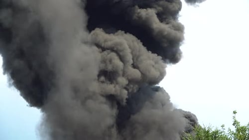 El humo negro se eleva hacia el cielo. Un gran incendio químico en el edificio de una fábrica. Cubiertas gruesas de humo negro