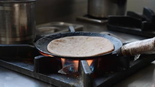 Adult Cooking Flatbread Over Flame in Kitchen