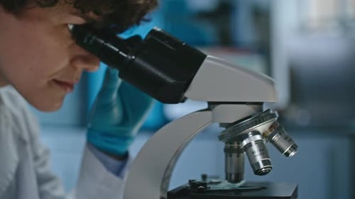 Scientist Looks Through Microscope in a Lab