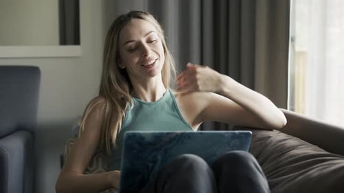 Frau auf dem Sofa zu Hause tätigt Videoanrufe mit Laptop zur Selbstisolation