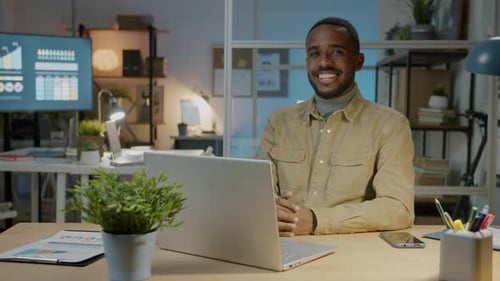 Slow Motion Portrait of Cheerful African American Businessman Sitting at Computer Desk in Office at