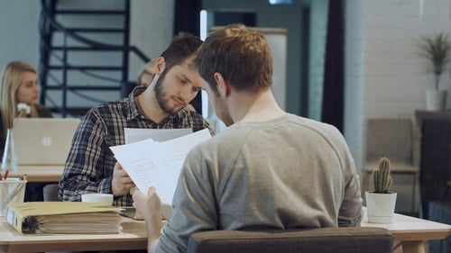Two Men Collaborating on Documents in Office
