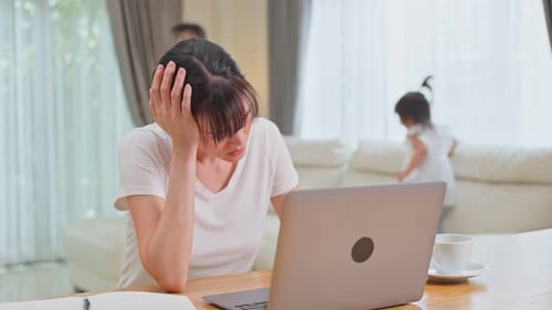 Asian businesswoman mother loss her concentration on job, frustrated from young girl making noise.