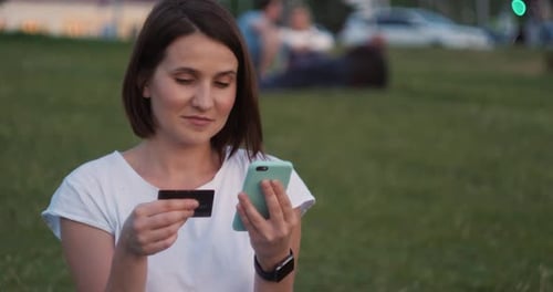 Student on Street with Credit Card and Phone Brunette Woman Sitting on the Bench and Makes Online