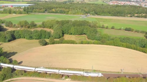 Pendlerzug fährt durch Landschaft und Ackerland