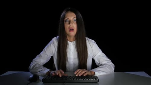 Terrified Woman Typing at Computer in Dark Room